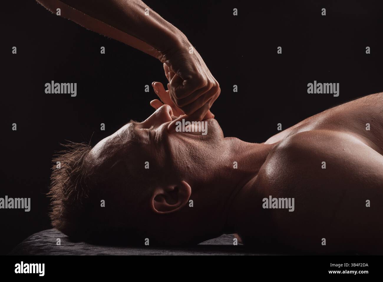 Nahaufnahme einer intraoralen Tiefengewebsmassage bei einem in einer Spa-Umgebung liegenden Mann. Stockfoto