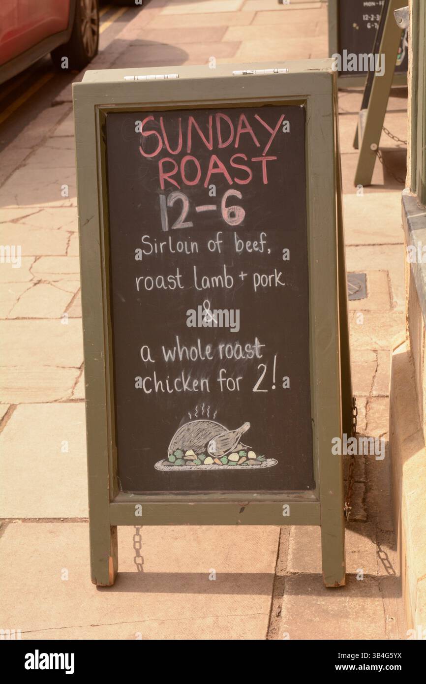 Schild mit der Tafel vor dem Pub mit der Aufschrift „Sunday Roast 12-6 Sirloin of Beef, Roast Lamb and Schweinefleisch and ganzer Braten Hähnchen für 2“ Stockfoto