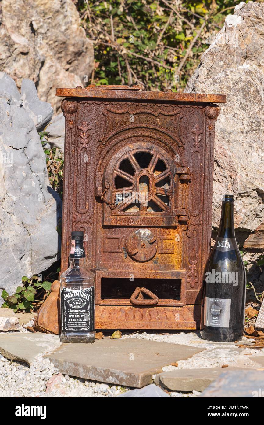 Theth, Shkoder, Albanien. Oktober 2024. Kleiner verrosteter Herd und Spirituosenflaschen. Stockfoto