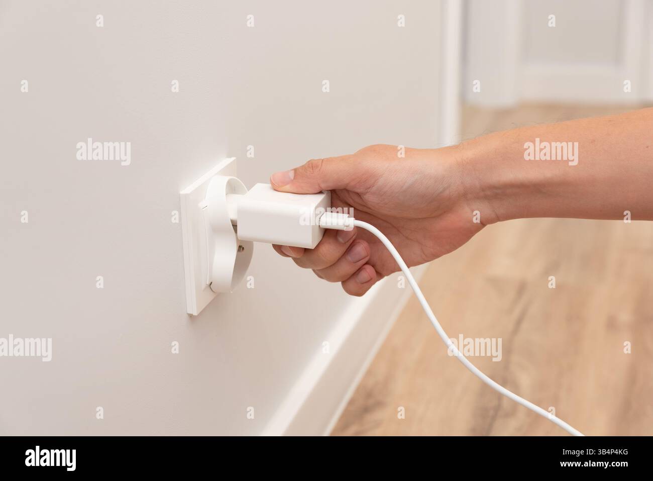Man steckt das elektrische Ladegerät in die intelligente Steckdose Stockfoto