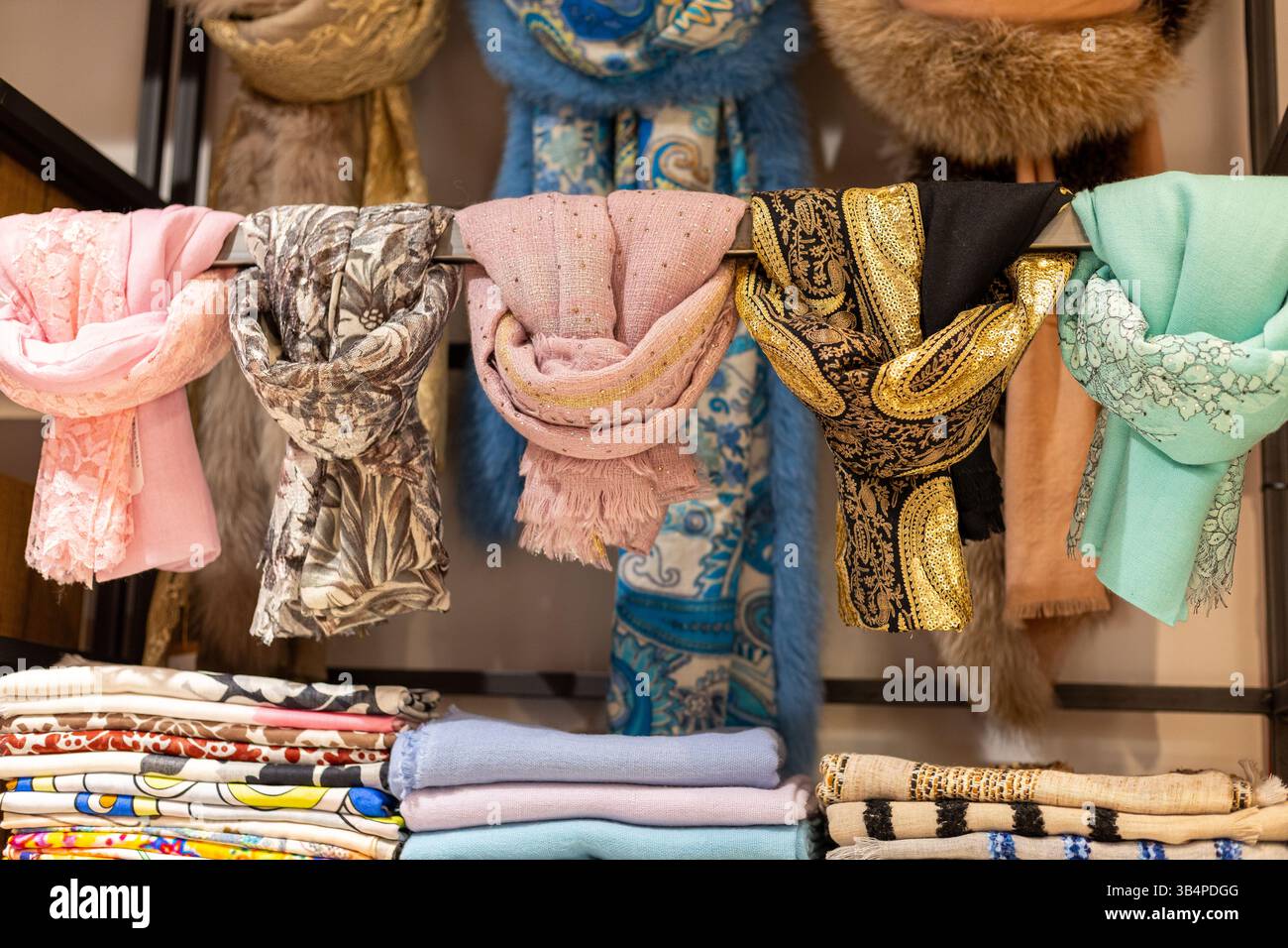 In einer Boutique hängen farbenfrohe Tücher. Jeder Schal zeigt einzigartige Muster und Texturen und zeigt eine Vielzahl von Farben und Stilen Stockfoto