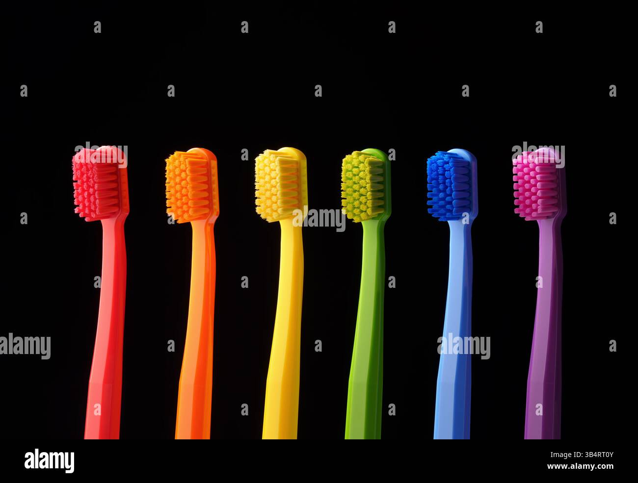 Mehrfarbige Kunststoffzahnbürsten auf schwarzem Hintergrund. Banner für die Zahnheilkunde. Farben des Regenbogens. Stockfoto