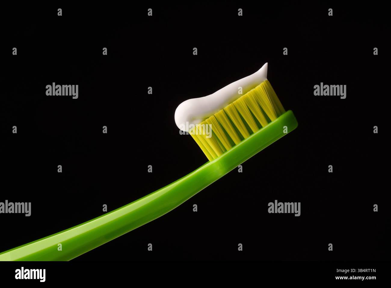 Grüne Plastikzahnbürste mit weißer Zahnpasta auf schwarzem Hintergrund. Professionelles Foto. Stockfoto