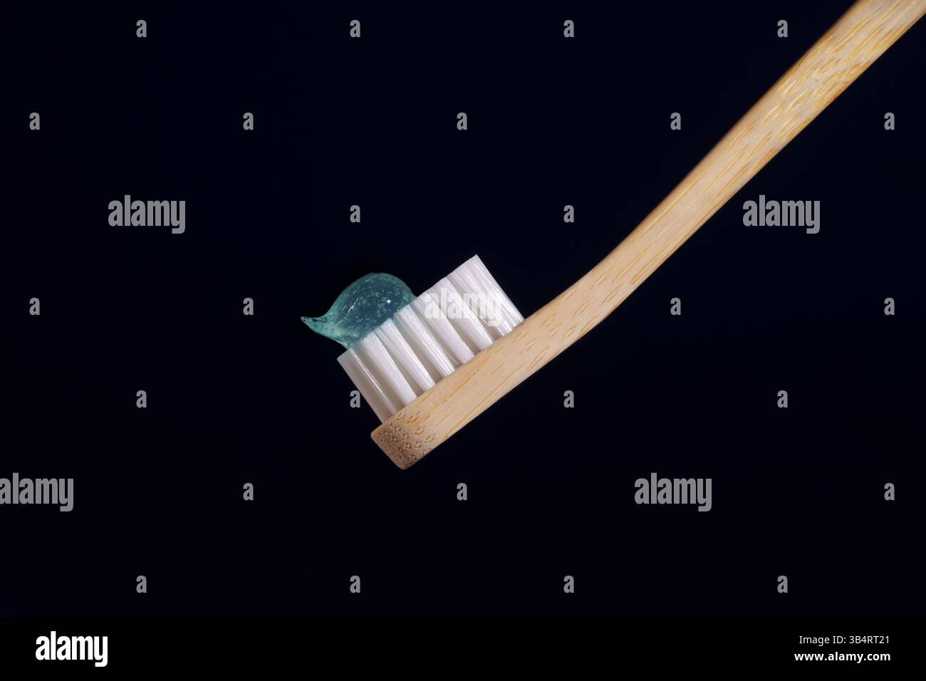 Bambuszahnbürste mit durchsichtiger blauer Zahnpasta auf dunkelblauem Hintergrund. Mundgesundheit. Stockfoto