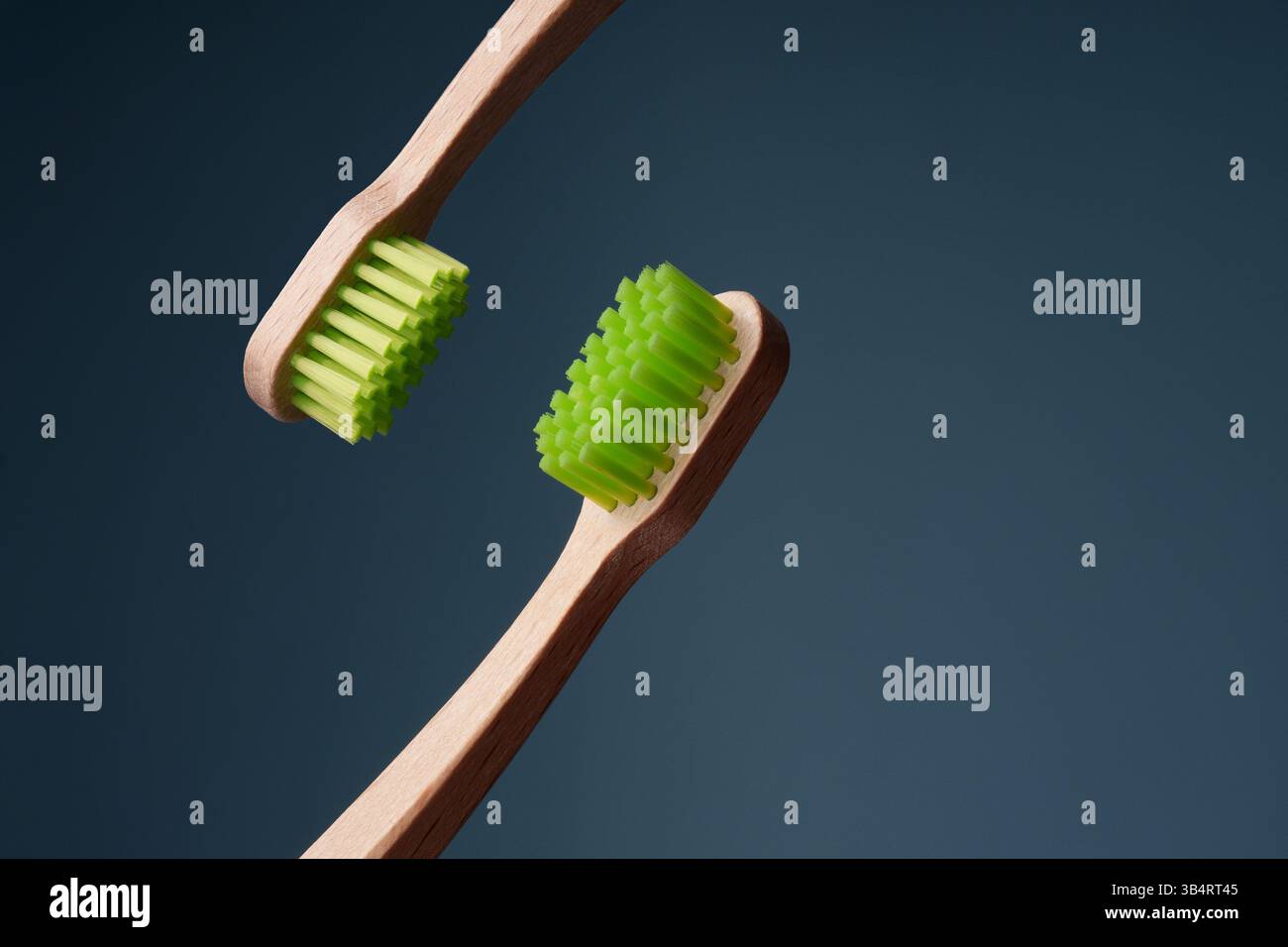 Zwei hölzerne Zahnbürsten mit grünem Schild auf blauem Hintergrund. Umweltfreundlichkeit. Stockfoto