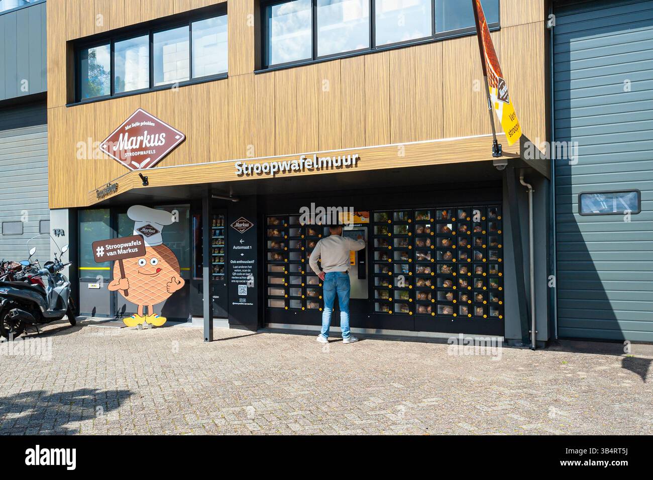 Man kauft eine Packung traditioneller holländischer Sirup-Waffeln aus einem Automaten hinter dem Glas gegen eine Gebühr. In Waddinxveen bei Gouda, Niederlande. Stockfoto