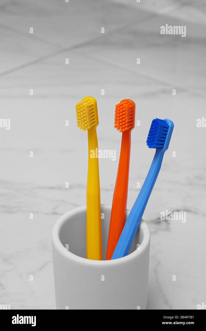 Drei farbige Pinsel in einem Glas im Badezimmer. Helles Foto. Mundhygiene. Stockfoto