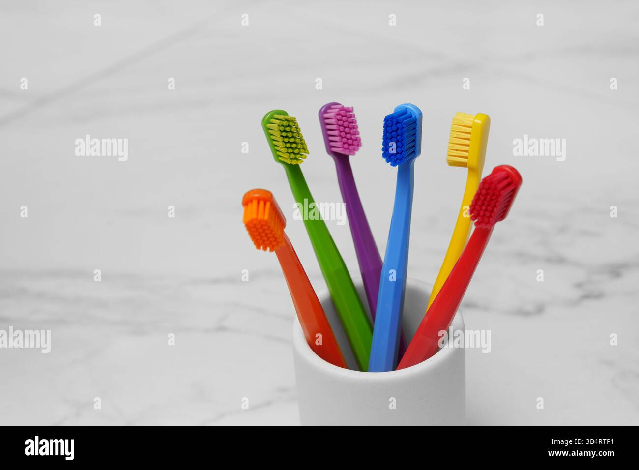 Sechs farbige Zahnbürsten in einem Glas im Badezimmer. Helles Foto. Platz für Text. Stockfoto