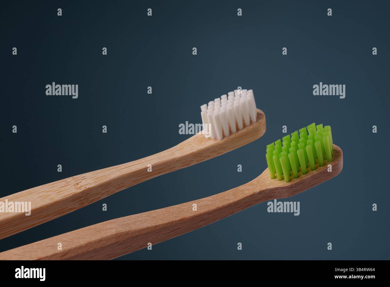 Zwei hölzerne Zahnbürsten mit grünen und weißen Schilden auf blauem Hintergrund. Leerzeichen für Text. Stockfoto