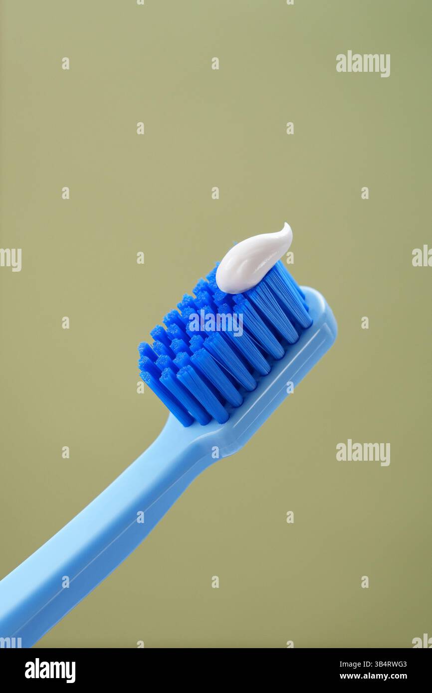 MINT-Hintergrund. Blaue Zahnbürste mit Zahnpasta auf grünem Hintergrund, Nahaufnahme. Stockfoto