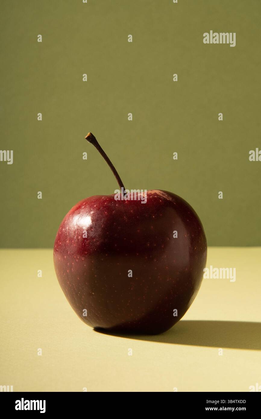 Nützlicher roter frischer Apfel auf einem sanften grünen Hintergrund mit einem Schatten. Stockfoto