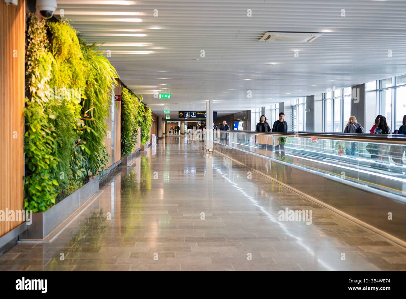 27. April 2025 Stockholm Schweden , Korridordurchfahrt zwischen den Terminals am Flughafen Arlanda mit Rolltreppe und Fluggästen Stockfoto