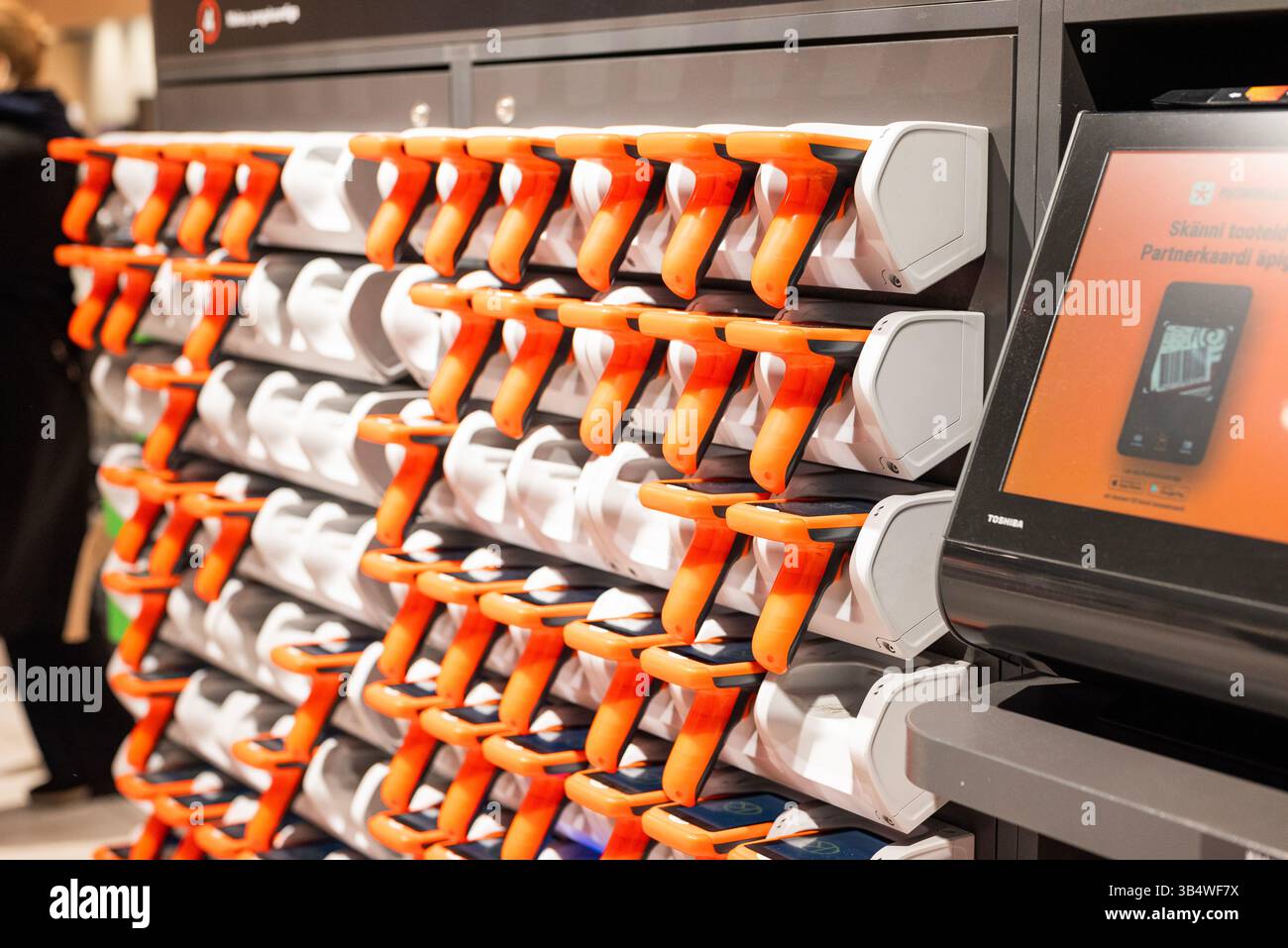 28. April 2025, Tallinn, Estland Ein Käufer verwendet einen tragbaren Barcode-Scanner, um Produkte in einem modernen Supermarkt zu scannen. Die Abbildung zeigt die Selbstbedienung Stockfoto