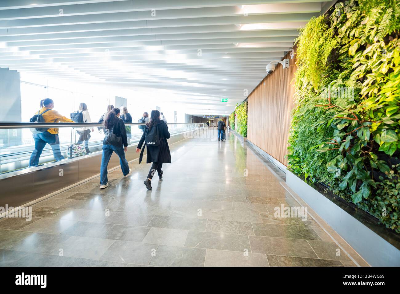27. April 2025 Stockholm Schweden , Korridordurchfahrt zwischen den Terminals am Flughafen Arlanda mit Rolltreppe und Fluggästen Stockfoto