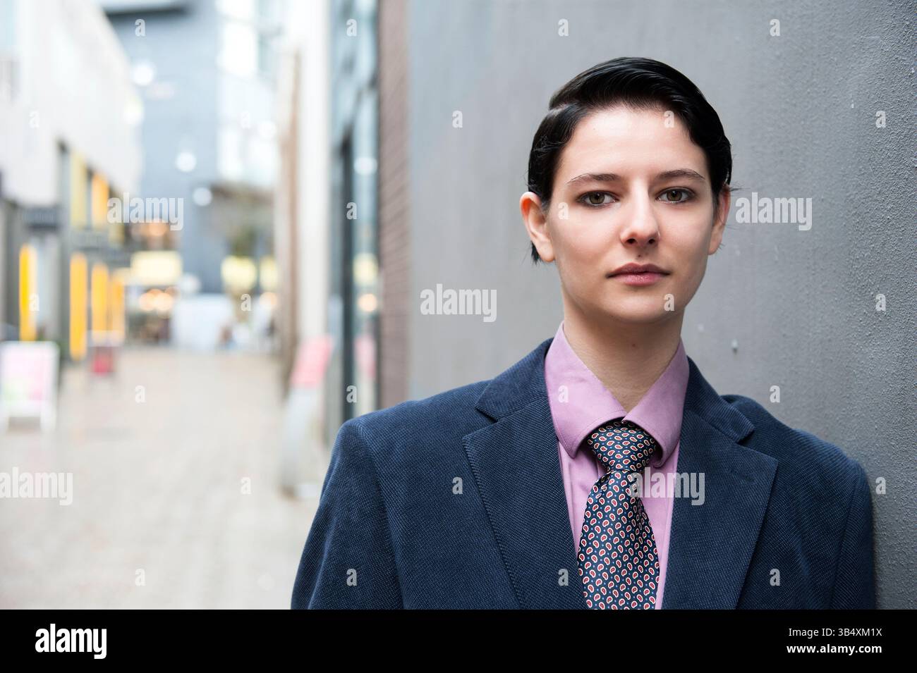 Eine junge Erwachsene, kaukasische Frau, gekleidet als modischer Mann, spaziert durch die Straßen der Stadt Tilburg, Niederlande. MR=JA Stockfoto