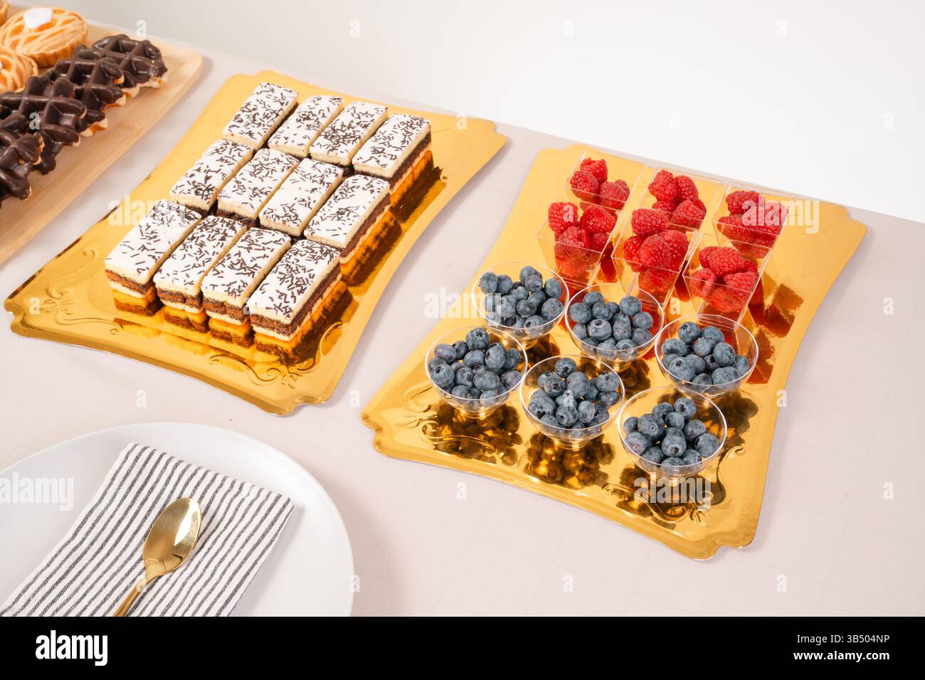 Elegantes Dessert- Und Obstangebot – Eistorten, Frische Beeren Und Goldene Tabletts Stockfoto