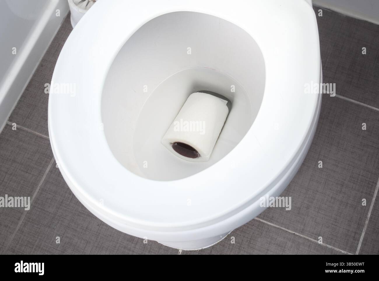 Verstopfte Toilettenschüssel mit Toilettenpapierrolle. Toilettenverstopfung oder Verstopfungsreinigung. Haustier- oder Kinderentwässerungsunfälle im Badezimmer oder Sabotageakte durch Disgruntle Ten Stockfoto