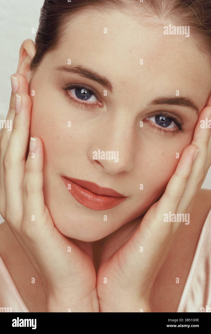 Nahporträt einer jungen Frau mit den Händen auf dem Gesicht. Stockfoto