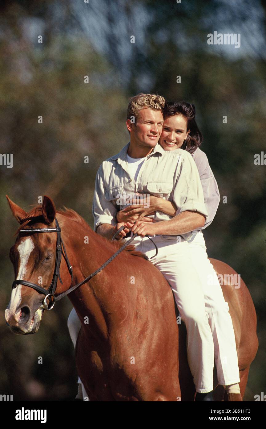Nahaufnahme eines jungen Paares draußen, das zusammen auf einem Pferd reitet. Stockfoto