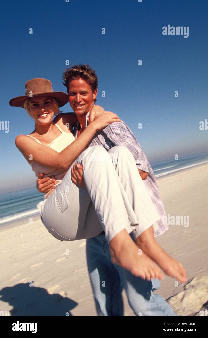 Lifestyle. Glückliches junges Paar am Strand. Mann, der eine Frau trägt. Stockfoto