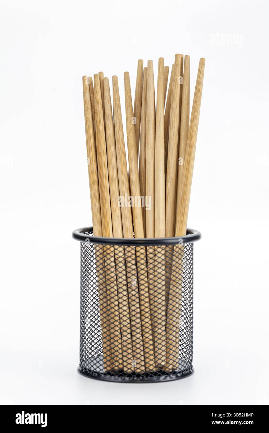 Holzstäbchen in Drahtkorb: Eine Sammlung von Holzstäbchen in einem eleganten schwarzen Drahtkorb. Stockfoto