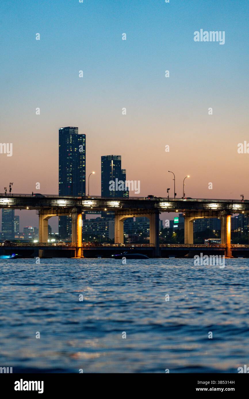 Skyline von Seoul City bei Sonnenuntergang mit Brücke über den Fluss und hohen Gebäuden im Hintergrund Stockfoto
