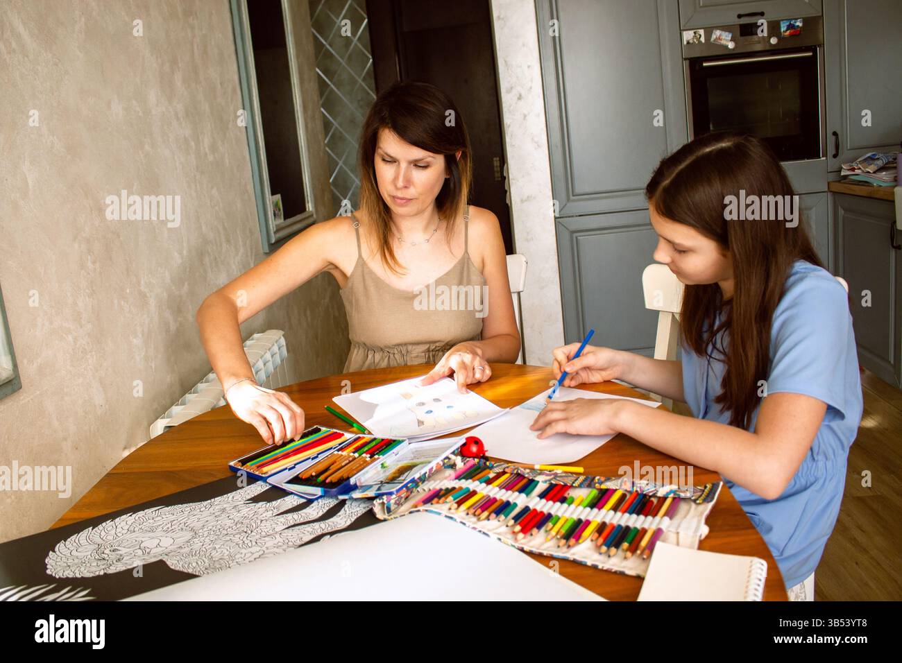 Mutter und Tochter lachen, während sie zusammen zeichnen, teilen zärtliche Momente. Berührende Szene sorgloser Kindheit und qualitativer elterlicher Beteiligung Stockfoto