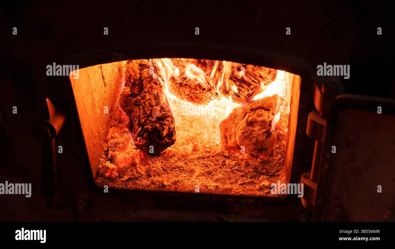 Nahaufnahme von brennendem Holz und glühender Glut in einem traditionellen Backofen. Die feurigen Orangetöne und die intensive Hitze zeigen die authentische Methode Stockfoto Nahaufnahme von brennendem Holz und glühender Glut in einem traditionellen Backofen. Die feurigen Orangetöne und die intensive Hitze zeigen die authentische Methode Stockfoto