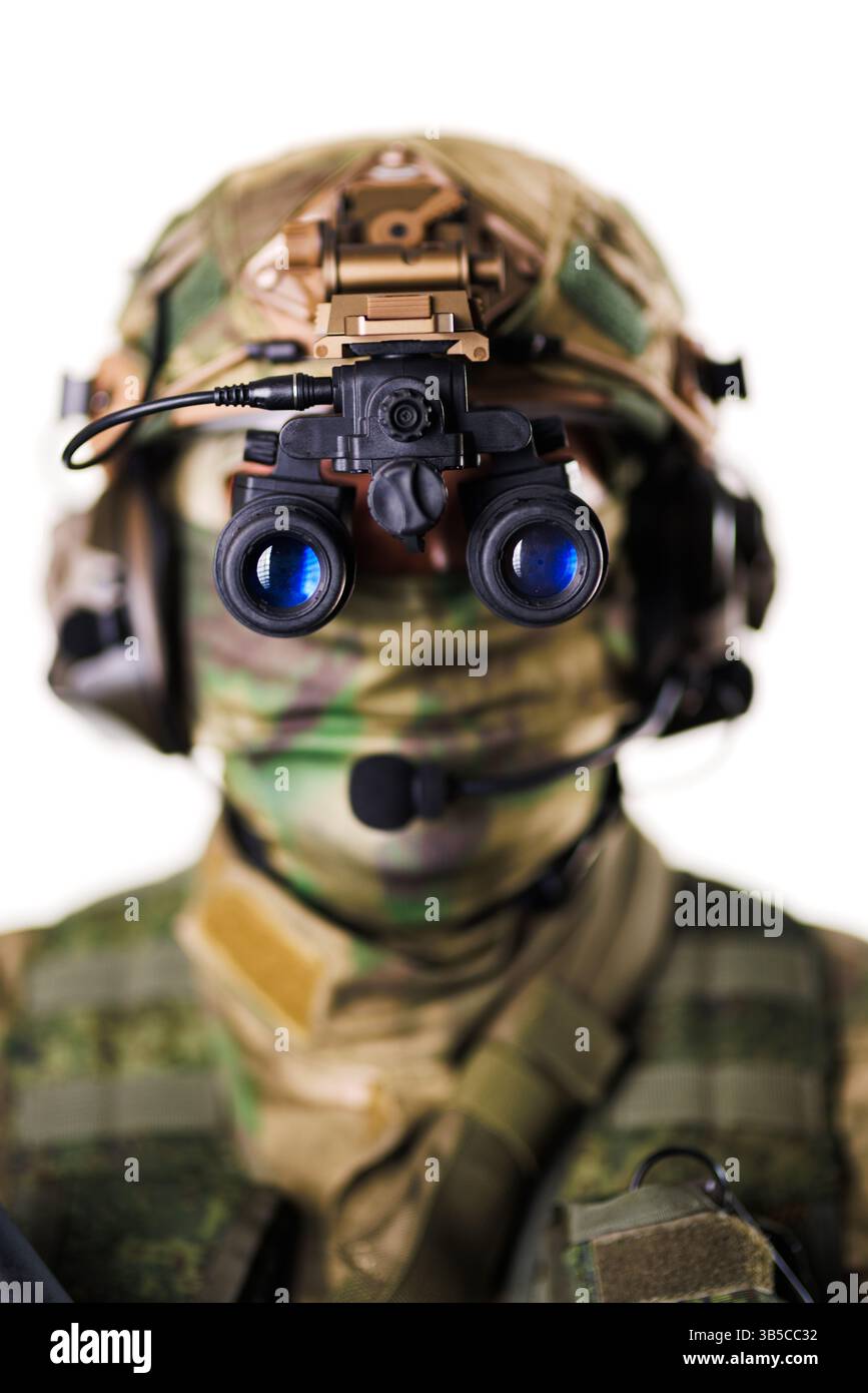 Ein Soldat, ausgestattet mit Nachtsichtgeräten und taktischer Ausrüstung, mit fortschrittlicher Militärtechnologie, posiert vor weißem Hintergrund. Stockfoto