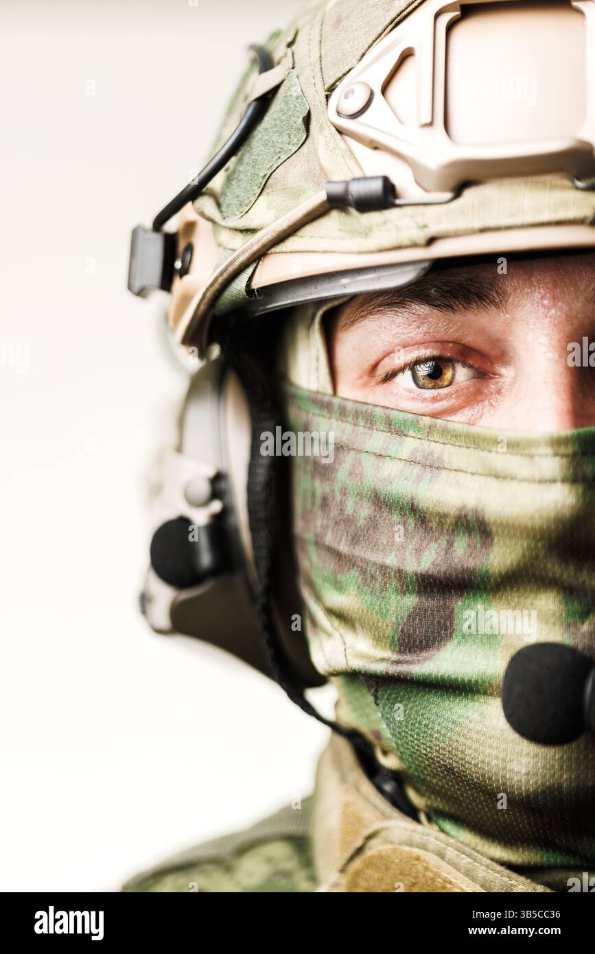 Ein Soldat mit Tarnausrüstung, Helm mit Kommunikationsausrüstung und Gesichtsschutz. Das Bild zeigt eine Nahansicht mit Betonung auf Stockfoto