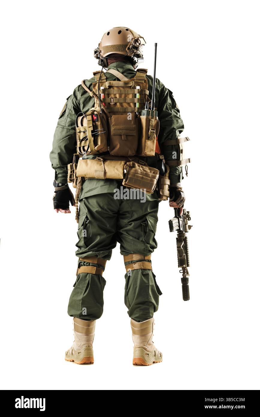 Ein stark ausgerüsteter taktischer Soldat in grüner Uniform, mit einer Schusswaffe, mit verschiedenen Ausrüstungen auf dem Rücken, gefangen gegen einen weißen Hintergras Stockfoto