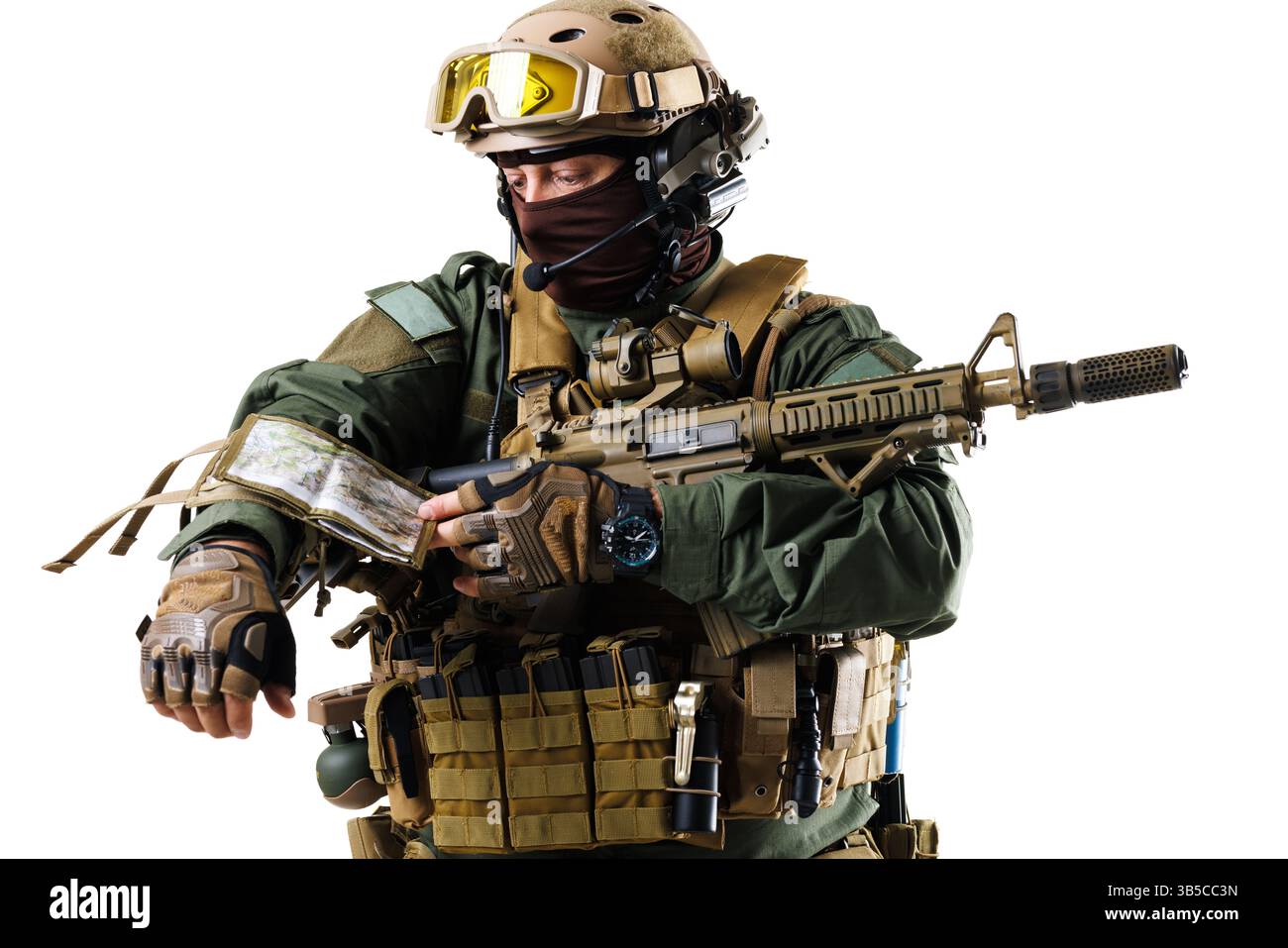 Ein bewaffneter Soldat mit fortschrittlicher Kampfausrüstung analysiert eine Karte auf ihrem Unterarm. Die professionelle Ausrüstung und die Pose heben die Bereitschaft hervor Stockfoto