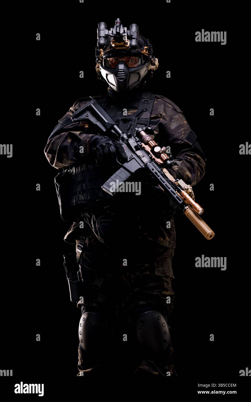 Porträt eines Soldaten in taktischer Ausrüstung mit schwarzem Anzug, Helm und moderner Waffe. Dramatisch vor dunklem Hintergrund aufgenommen, symbolisiert Stockfoto
