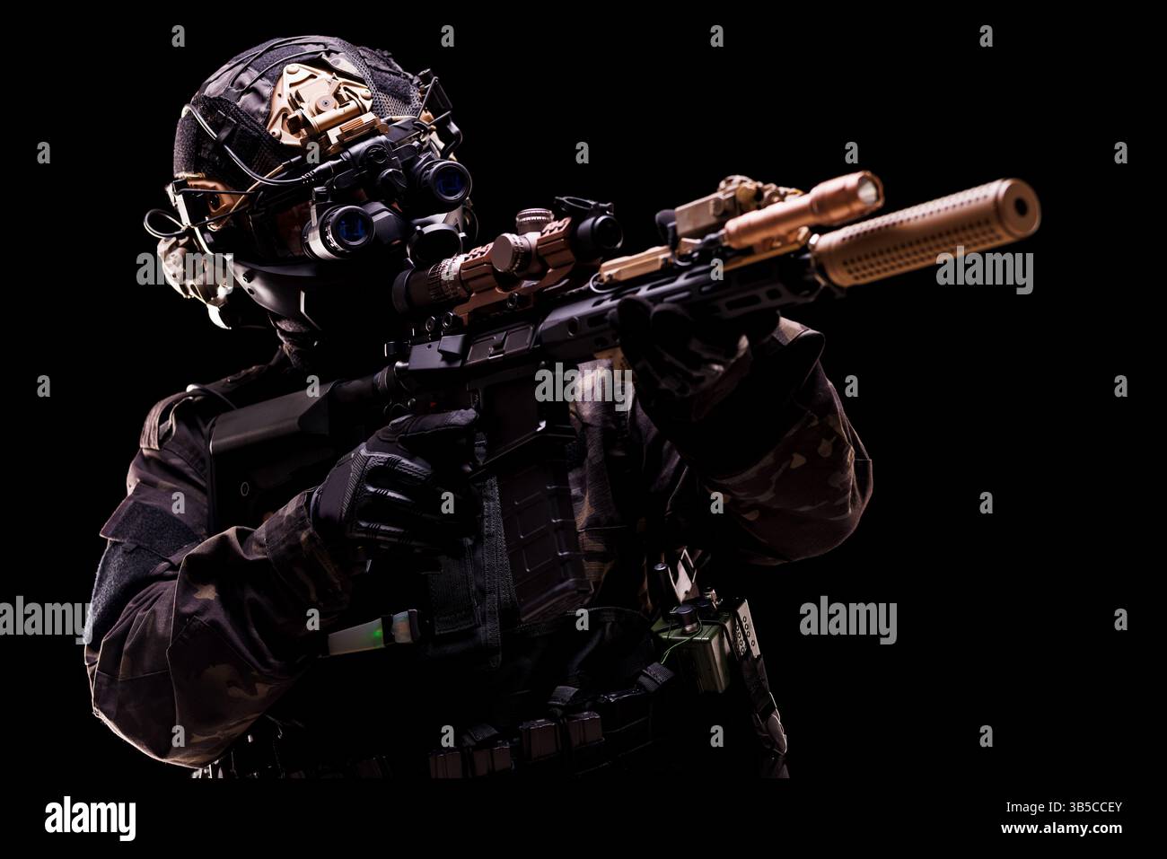 Ein hochausgestatteter Agent in taktischer Ausrüstung zielt auf eine Tarnwaffe, die für eine Mission vorbereitet ist. Das Foto zeigt fortschrittliche Technologie und Vorsorge Stockfoto