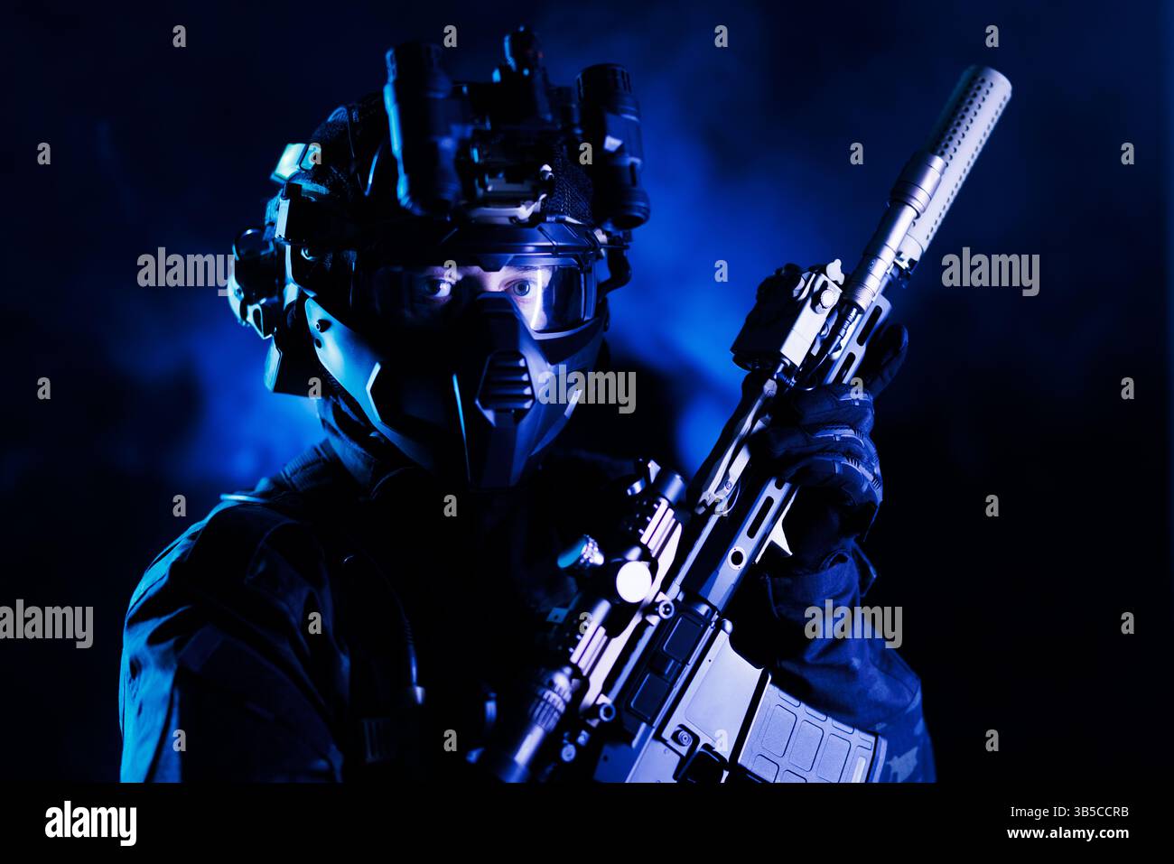 Ein taktischer Soldat in Tarnausrüstung, ausgestattet mit Nachtsicht und Gewehr, in einem dramatischen, blau beleuchteten Hintergrund, der an Präzision und Vorbereitung erinnert Stockfoto