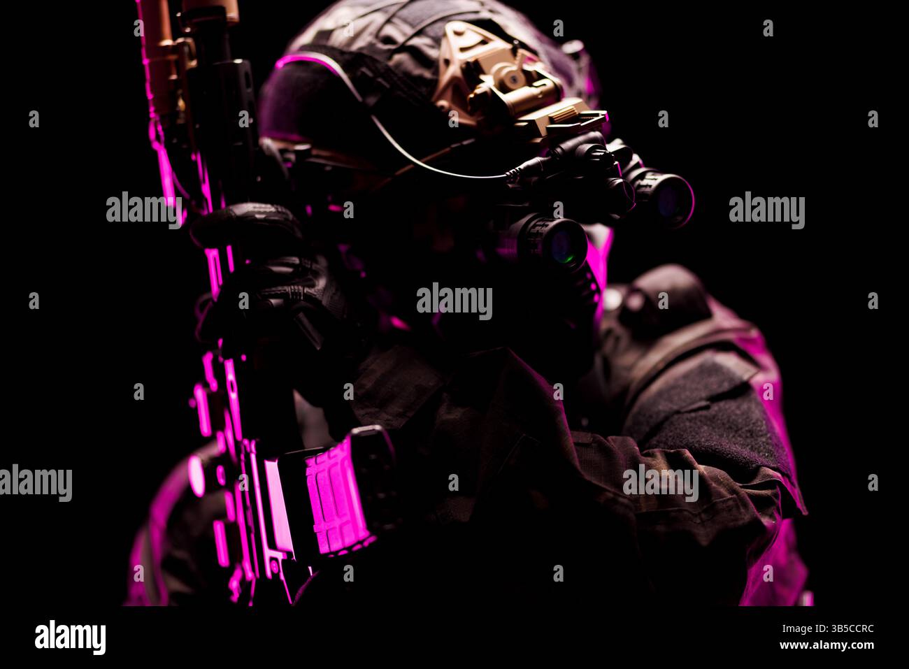 Eine Spezialeinheit, ausgestattet mit fortschrittlichen Nachtsichtgeräten und taktischer Ausrüstung, beleuchtet in dramatischer rosa Beleuchtung auf einem schwarzen Rücken Stockfoto