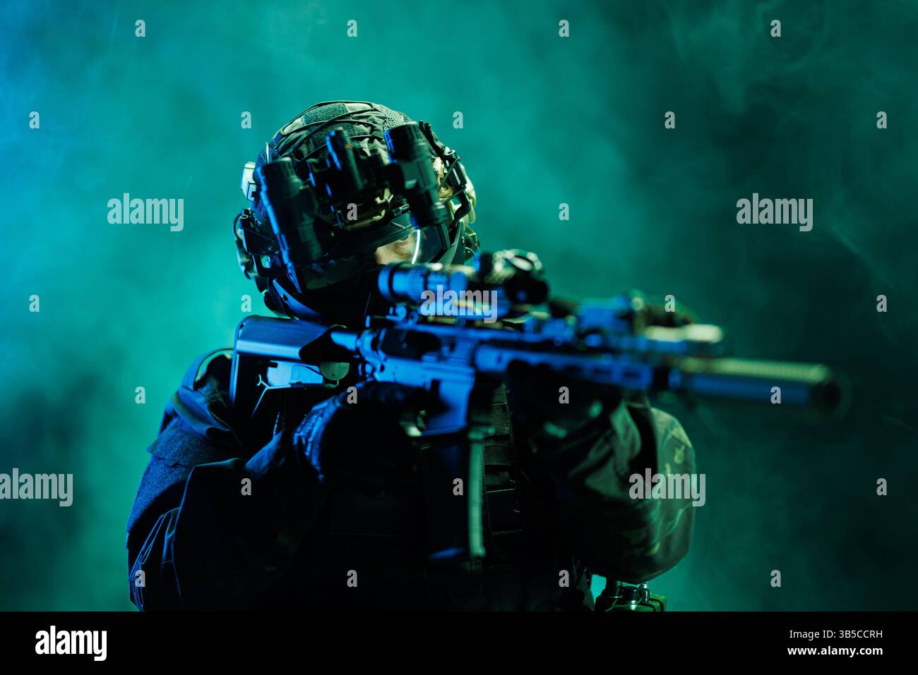 Ein stark ausgerüsteter taktischer Soldat mit Nachtsichtbrille, die auf ein fortschrittliches Gewehr gerichtet ist, hervorgehoben durch dynamisches, atmosphärisches grünes Licht. Die Szene Stockfoto