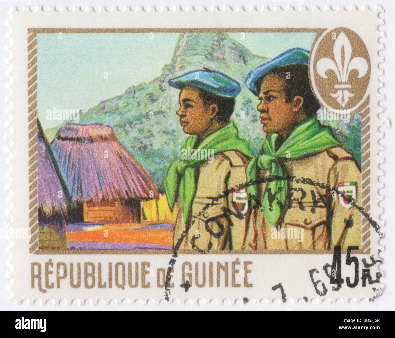 GUINEA - 1. Juli 1969: 45 Franken Gold- und mehrfarbige Briefmarke, die Pionniers, Pfadfinder, Strohhütten und Berge zeigt. Ausgestellt zu Ehren der Pfadfinder von Guinea. Pionnier de Guinee, nationale Bewegung. Scouting, auch bekannt als Scout Movement, ist eine weltweite Jugendbewegung, die die Scout-Methode verwendet und sich im ersten Jahrzehnt des 20. Jahrhunderts etabliert hat. Sie folgt einem informellen Bildungssystem mit Schwerpunkt auf praktischen Outdoor-Aktivitäten, wie Camping, Holzwerkstatt, Wassersport, Wandern, Rucksack und Sport Stockfoto
