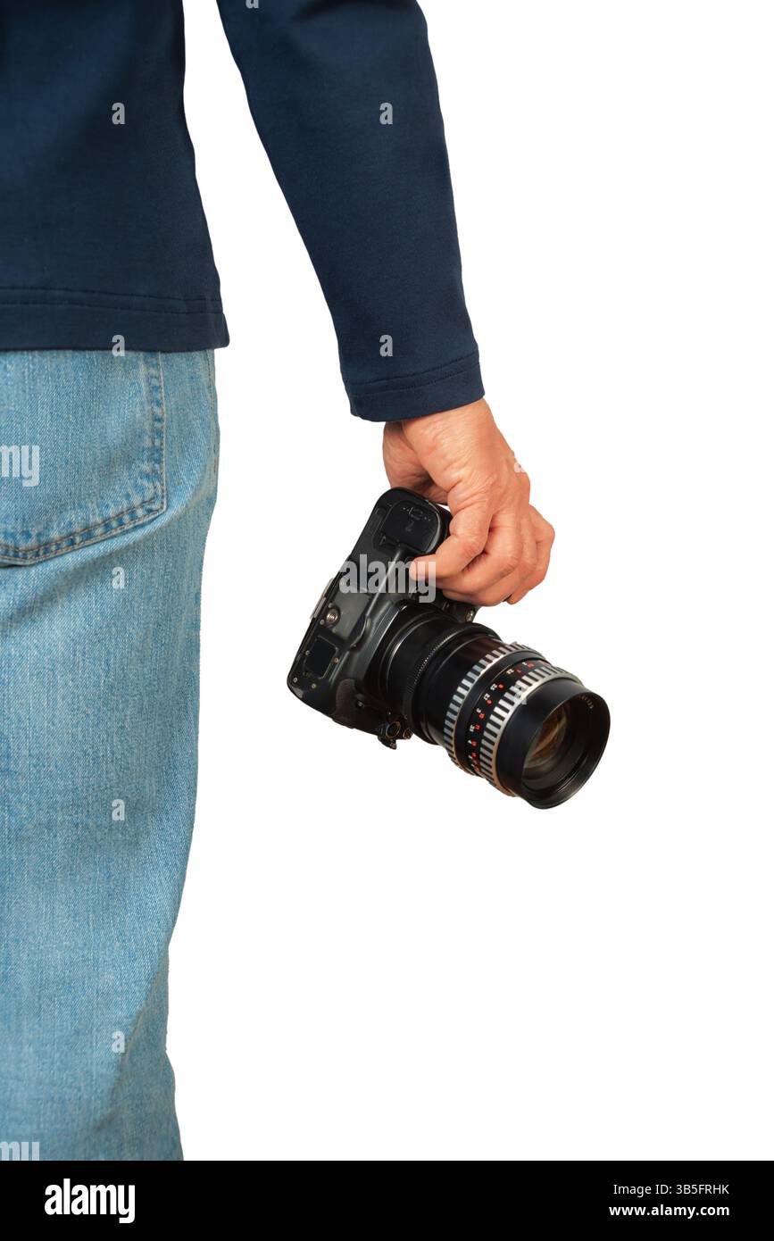 Die Person hält eine professionelle Kamera mit Objektiv in einem legeren Outfit, um Momente während des Tages festzuhalten. Stockfoto