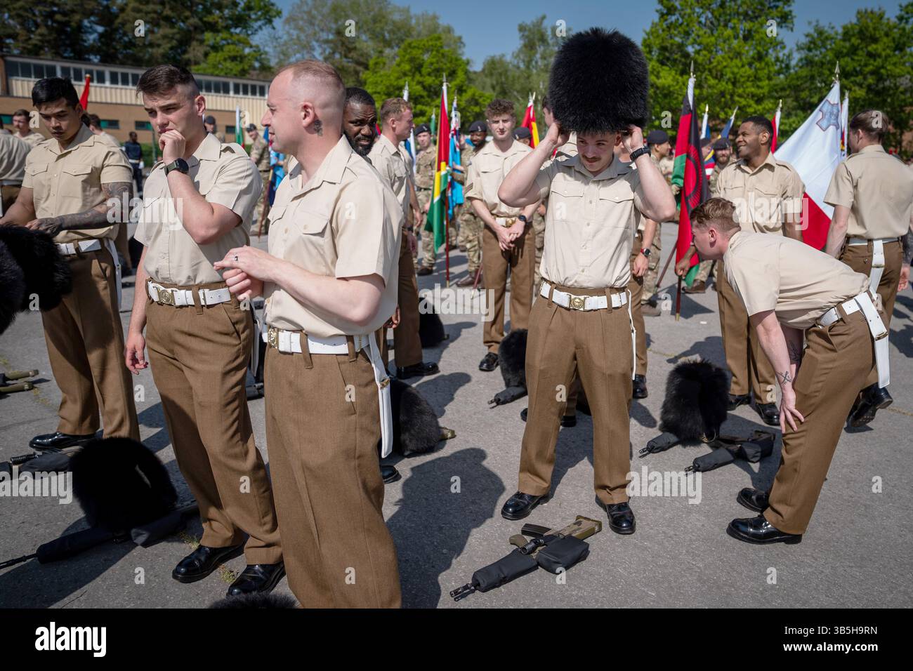 Mitglieder der Streitkräfte zogen ihre Bärenfellmützen an, während einer Prozession zur Vorbereitung des 80. Jahrestages des VE Day am 5. Mai im Army Training Centre Pirbright in Woking, Surrey. Bilddatum: Freitag, 2. Mai 2025. Stockfoto