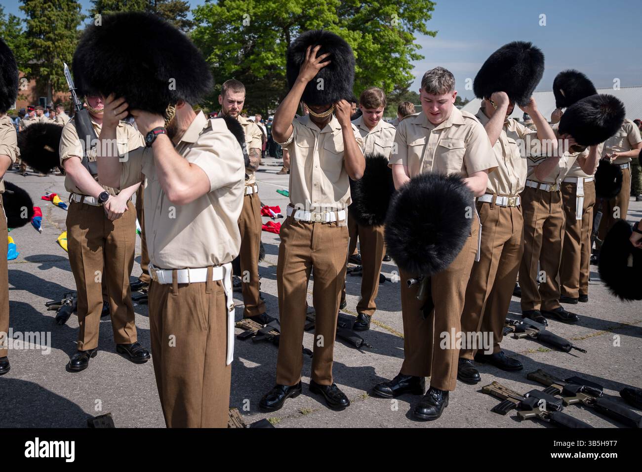 Mitglieder der Streitkräfte zogen ihre Bärenfellmützen an, während einer Prozession zur Vorbereitung des 80. Jahrestages des VE Day am 5. Mai im Army Training Centre Pirbright in Woking, Surrey. Bilddatum: Freitag, 2. Mai 2025. Stockfoto