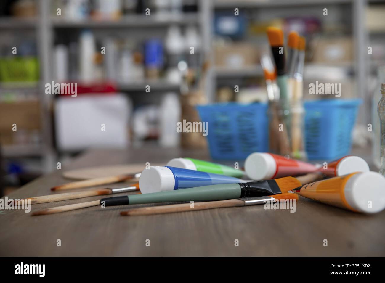Eine bunte Auswahl an Kunstgegenständen und Pinseln, die auf einem Holztisch in einer künstlerischen Umgebung angeordnet sind Stockfoto