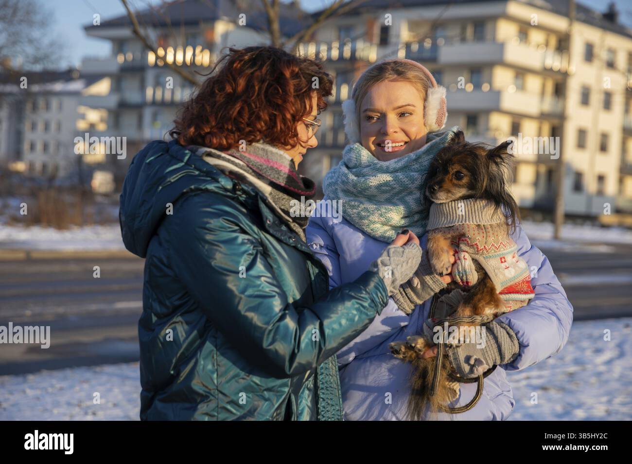 Silhouetten von zwei Frauen von der Taille nach oben. Die Frauen reden und lächeln. Sie sind in warmen Kleidern gekleidet, während der Schnee liegt. Einer der Frauen Stockfoto