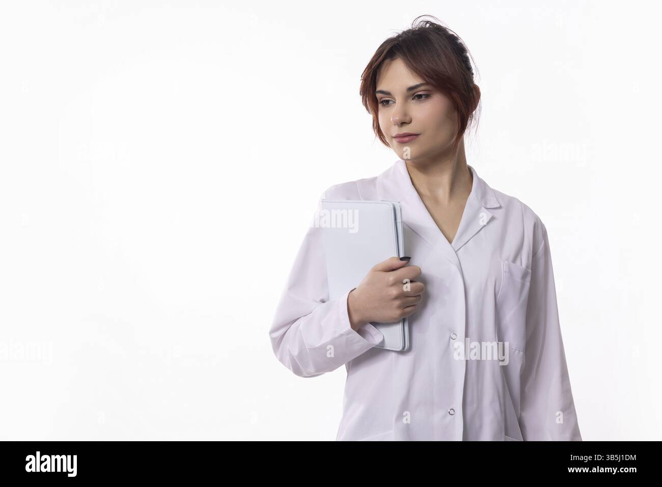 Eine selbstbewusste medizinische Fachkraft in einem knusprigen weißen Fell hält nachdenklich eine Tablette Stockfoto