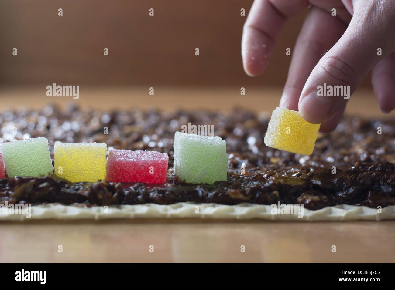 Schokolade topping mit wallnuts auf Kuchen Kruste für gerollte Schokoladenkuchen mit Gelee Bonbons Stockfoto