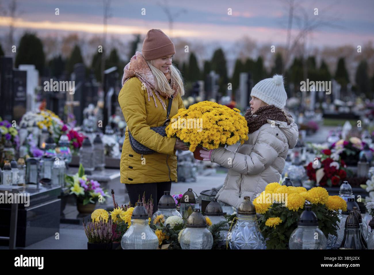 Zwei Individuen versammeln sich auf einem ruhigen Friedhof, um ihre Lieben zu ehren, umgeben von Blumen und Erinnerungen Stockfoto