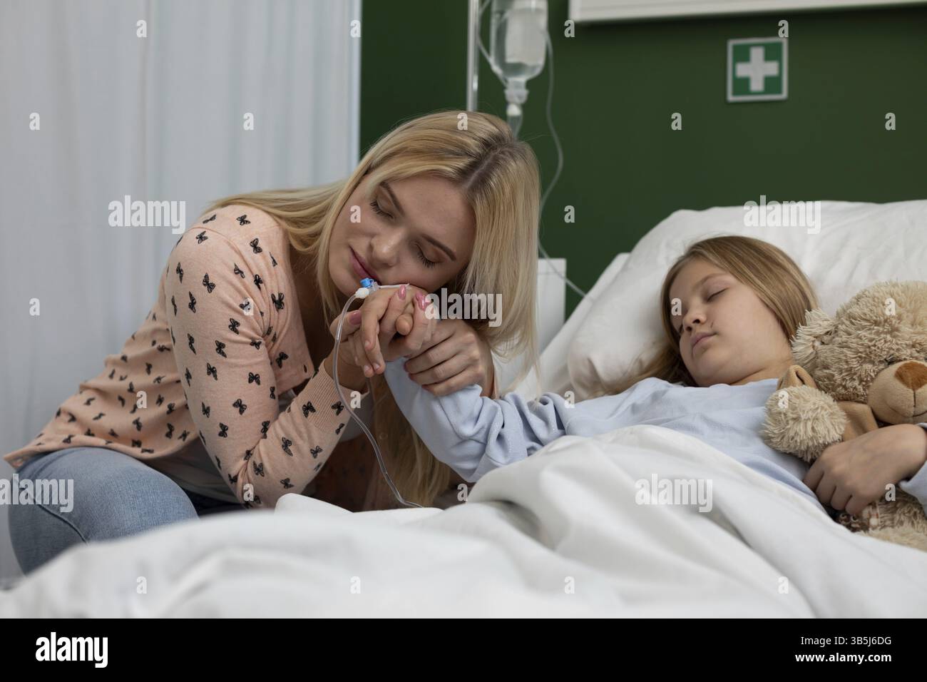 Ein herzlicher und pflegender Moment, der zwischen einer fürsorglichen Mutter und ihrer Tochter in einem Krankenhauszimmer geteilt wird Stockfoto
