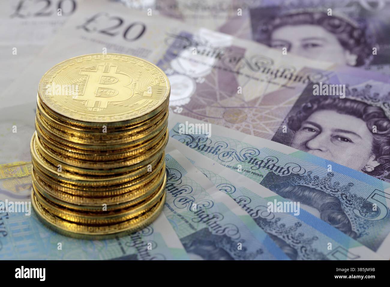 Virtuelle Kryptowährung Geld Bitcoin Goldmünzen auf britischen Pfund Sterling Banknoten mit Gesichtern von Königin Elisabeth II Stockfoto