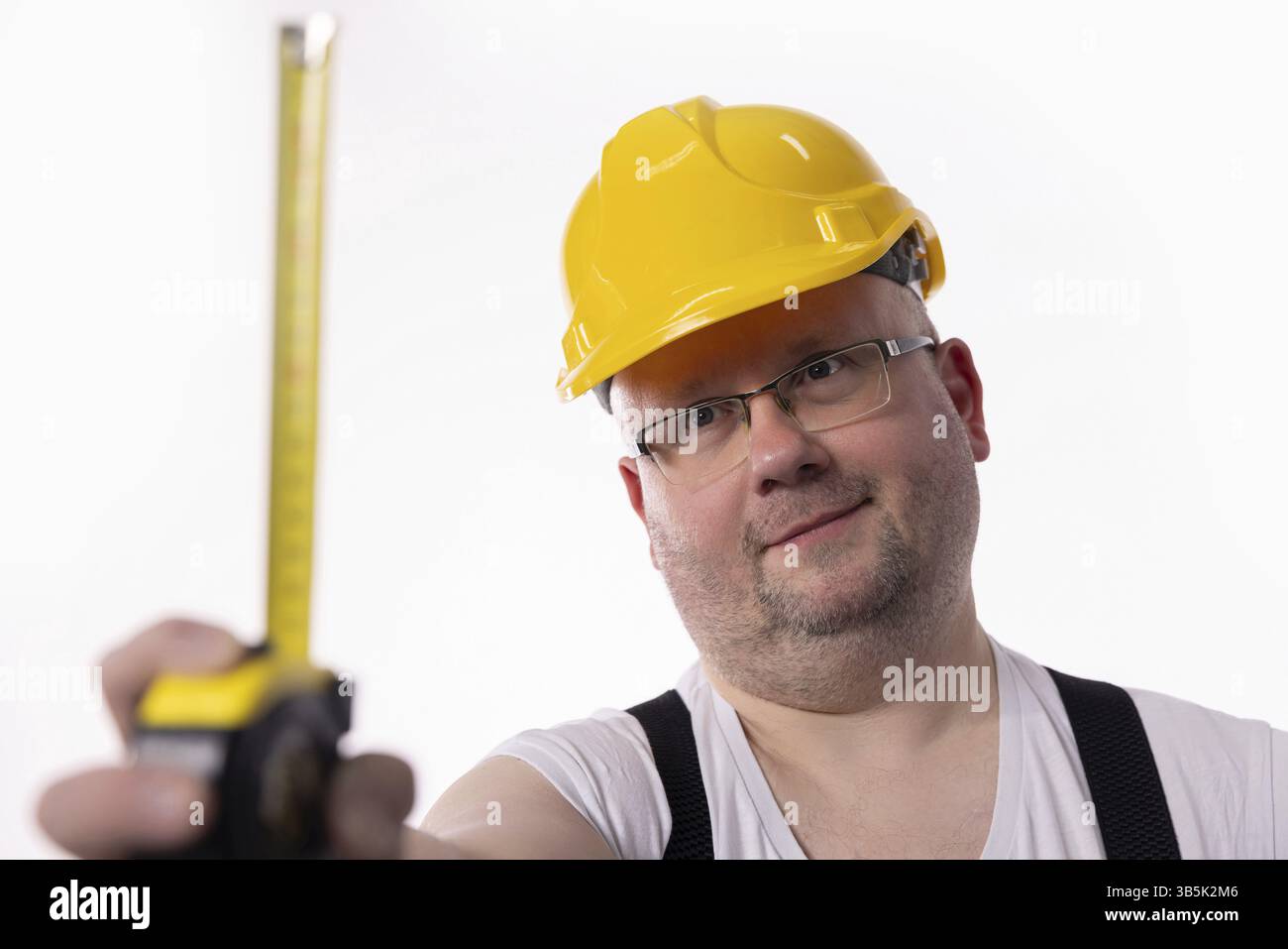 Ein Bauarbeiter ist mit einem Maßband dabei, das die Bedeutung von Sicherheit und Präzision im Feld verdeutlicht Stockfoto