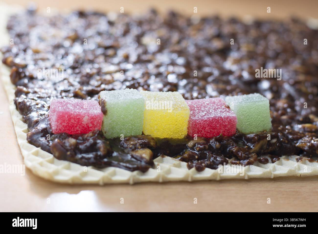 Schokolade topping mit wallnuts auf Kuchen Kruste für gerollte Schokoladenkuchen mit Gelee Bonbons Stockfoto